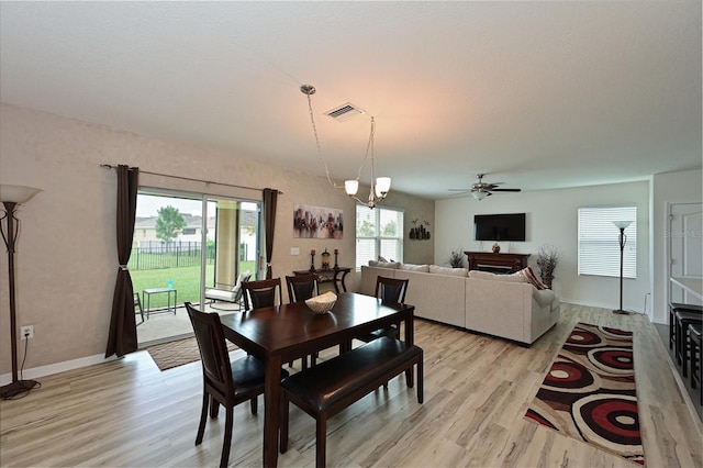 dining room featuring light wood-type flooring and ceiling fan with notable chandelier