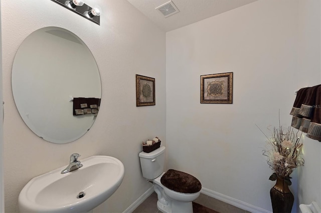 bathroom featuring toilet, sink, and a textured ceiling