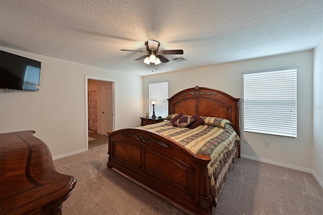 bedroom with a textured ceiling, ensuite bathroom, light carpet, and ceiling fan