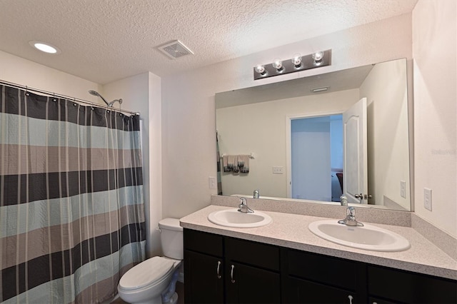 bathroom with toilet, vanity, a textured ceiling, and walk in shower