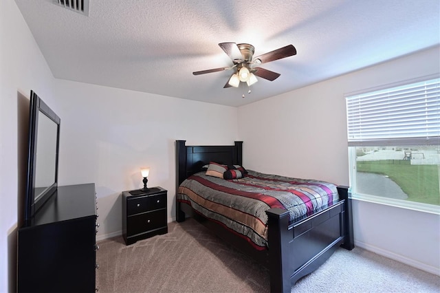 carpeted bedroom with ceiling fan and a textured ceiling