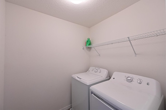 clothes washing area featuring a textured ceiling and washer and dryer