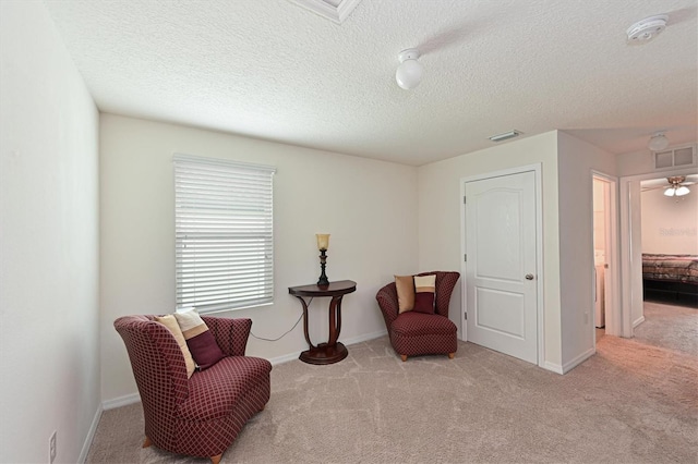 living area with a textured ceiling and light carpet