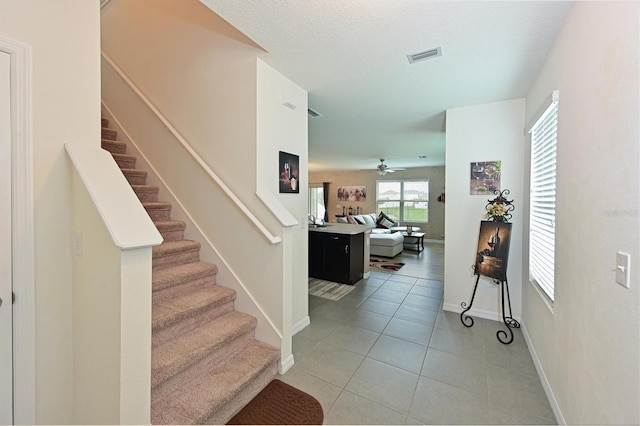 stairway featuring ceiling fan and tile patterned flooring