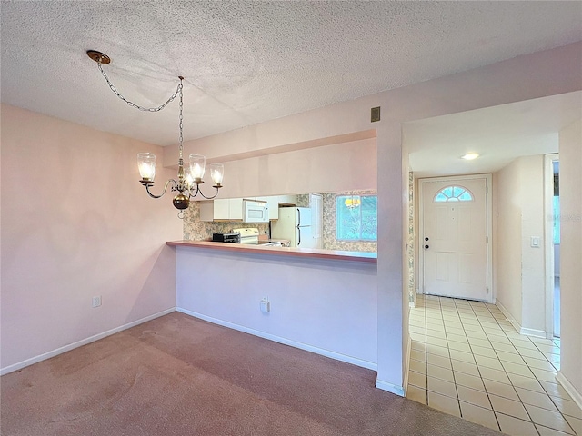 kitchen with white appliances, a textured ceiling, kitchen peninsula, hanging light fixtures, and light carpet