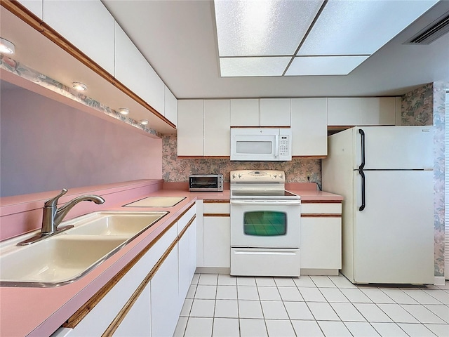 kitchen with white appliances, light tile patterned flooring, sink, and white cabinets