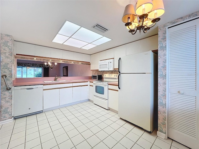 kitchen featuring white appliances, white cabinetry, sink, and an inviting chandelier