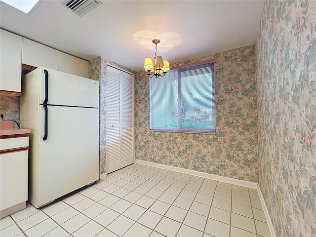 kitchen featuring light tile patterned flooring, pendant lighting, white cabinets, a notable chandelier, and white refrigerator