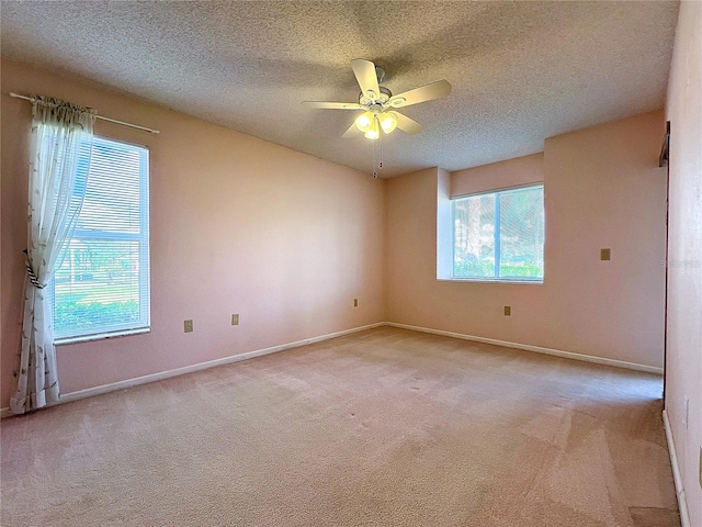 carpeted spare room featuring a textured ceiling, ceiling fan, and a wealth of natural light