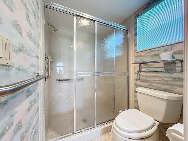 bathroom featuring a shower with shower door, toilet, and tile patterned flooring