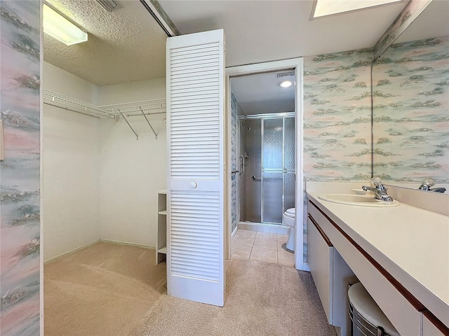 bathroom with vanity, a textured ceiling, toilet, and walk in shower