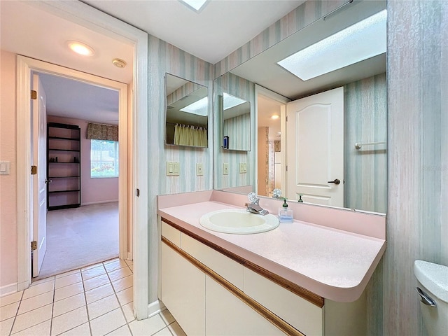 bathroom featuring vanity, tile patterned floors, toilet, and a skylight