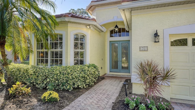 view of exterior entry with a garage and french doors