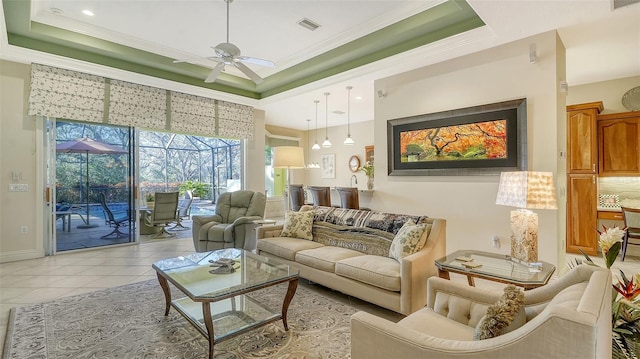 living room with a raised ceiling, ceiling fan, and crown molding