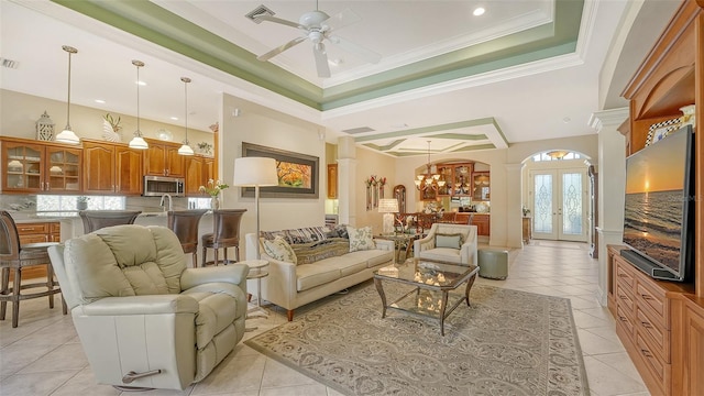 tiled living room with french doors, sink, a raised ceiling, crown molding, and ceiling fan with notable chandelier