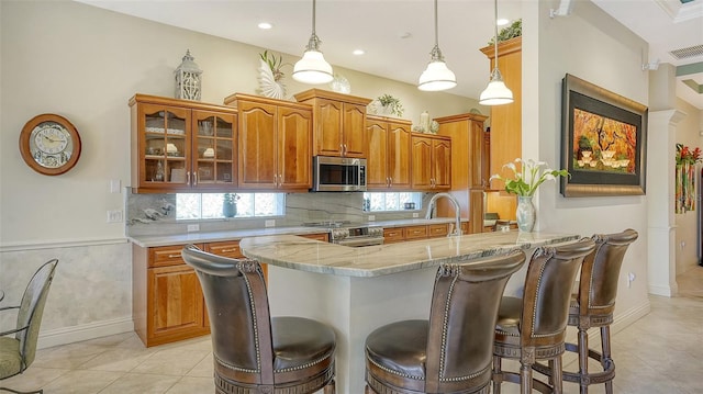 kitchen with kitchen peninsula, a kitchen breakfast bar, stainless steel appliances, and hanging light fixtures