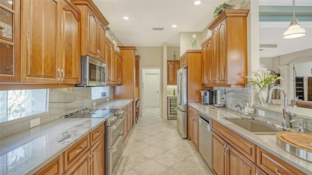 21 Bayhead Ln, Osprey, FL 34229 - kitchen with stainless steel appliances, brown cabinetry, light stone countertops, and recessed lighting