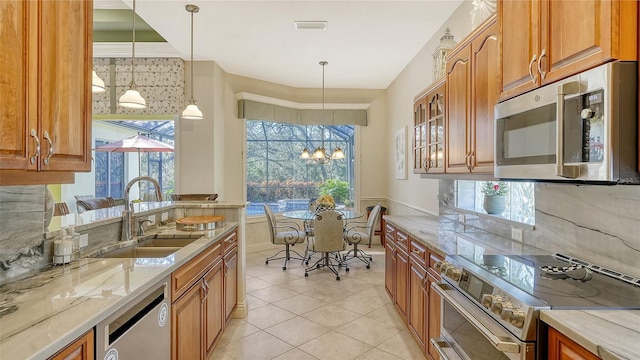 21 Bayhead Ln, Osprey, FL 34229 - kitchen featuring stainless steel appliances, a sink, light stone counters, brown cabinets, and a wainscoted wall