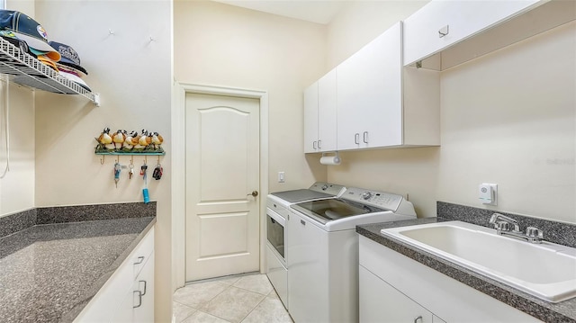 washroom featuring washing machine and dryer, sink, light tile patterned flooring, and cabinets