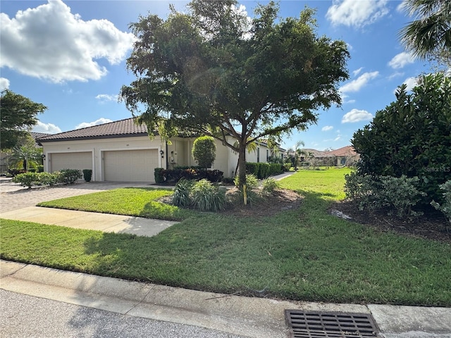 view of front of house featuring a front yard, driveway, a tiled roof, and an attached garage