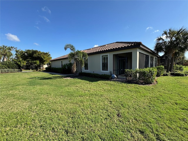 exterior space with a tile roof, a lawn, and stucco siding