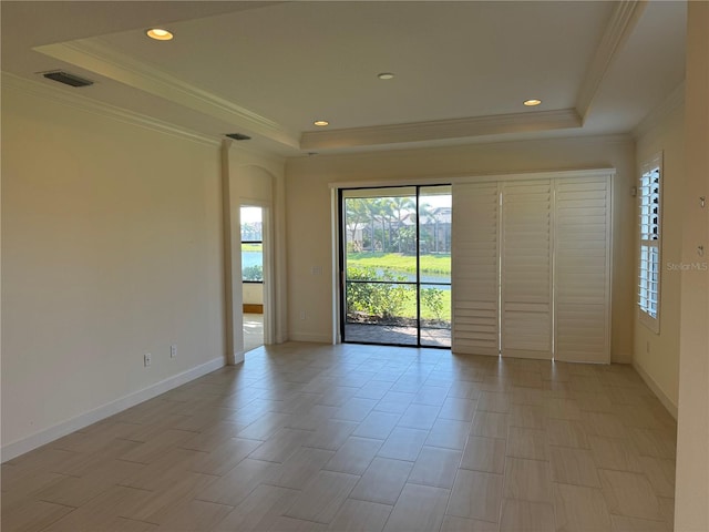 spare room with a raised ceiling, visible vents, crown molding, and baseboards