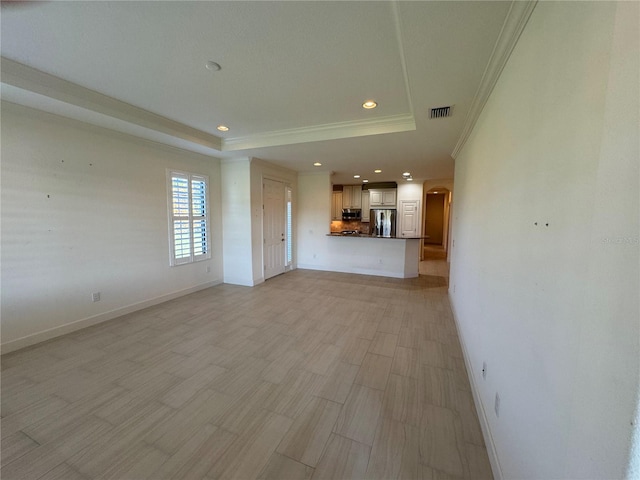 unfurnished living room featuring visible vents, crown molding, a tray ceiling, and baseboards