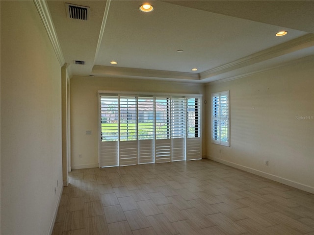 spare room with baseboards, visible vents, a raised ceiling, and crown molding