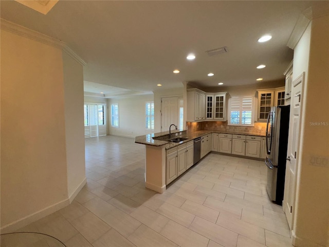 kitchen with glass insert cabinets, open floor plan, a peninsula, stainless steel appliances, and a sink