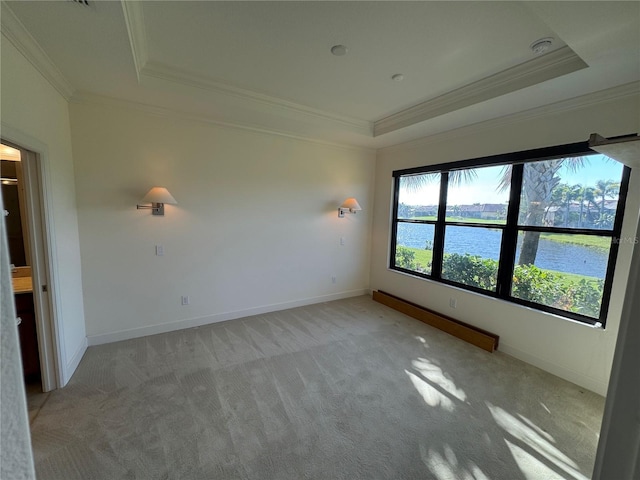 unfurnished room with a tray ceiling, crown molding, a water view, light carpet, and baseboards