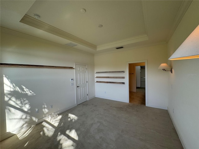 unfurnished room featuring ornamental molding, carpet floors, a tray ceiling, and visible vents