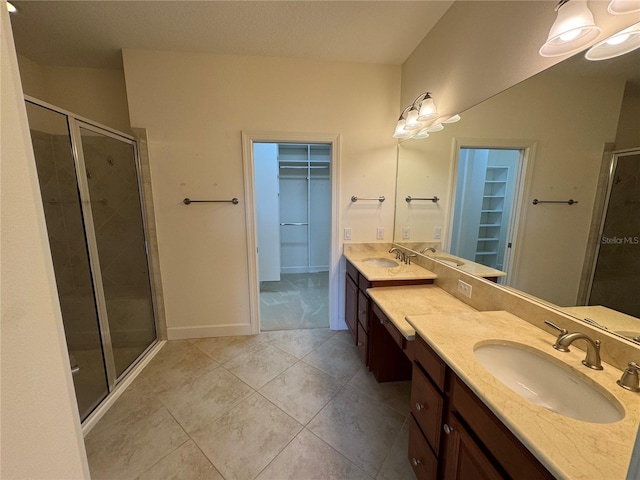 bathroom with double vanity, a shower stall, a walk in closet, and a sink