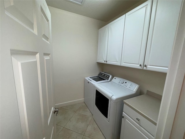 laundry area featuring washing machine and dryer, cabinet space, baseboards, and light tile patterned flooring