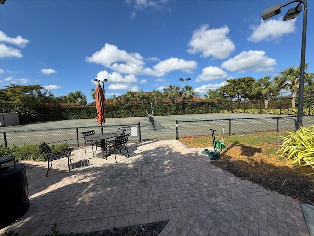 view of property's community featuring a tennis court and fence