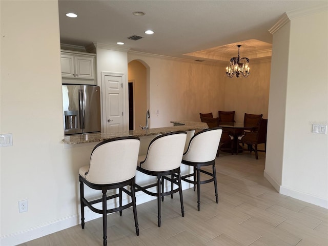 kitchen with pendant lighting, visible vents, dark stone countertops, a peninsula, and stainless steel fridge with ice dispenser