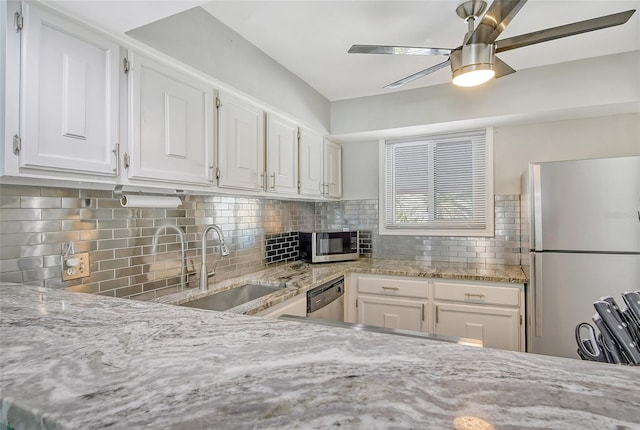 kitchen featuring decorative backsplash, white cabinets, stainless steel appliances, and sink