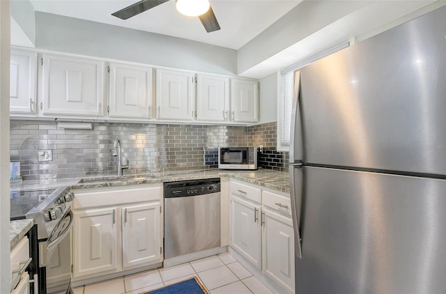 kitchen featuring sink, white cabinets, light tile patterned flooring, appliances with stainless steel finishes, and light stone counters