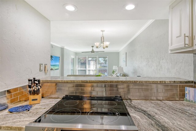 kitchen featuring decorative backsplash, black stove, ornamental molding, a notable chandelier, and white cabinets