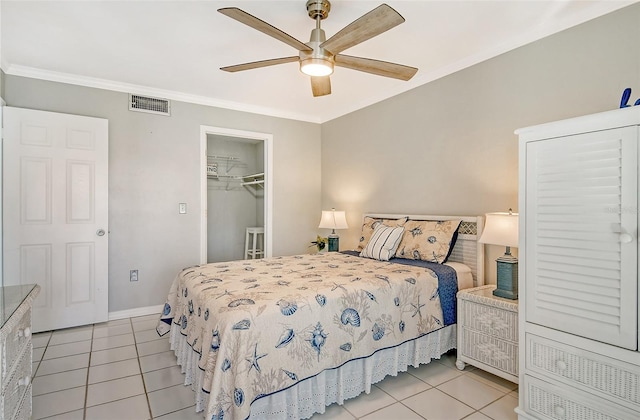 tiled bedroom with a spacious closet, ornamental molding, a closet, and ceiling fan