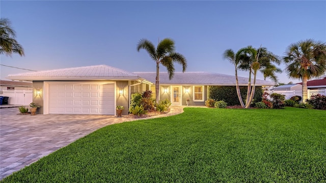 ranch-style home featuring a garage and a yard