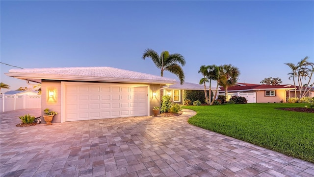 ranch-style home featuring a lawn and a garage