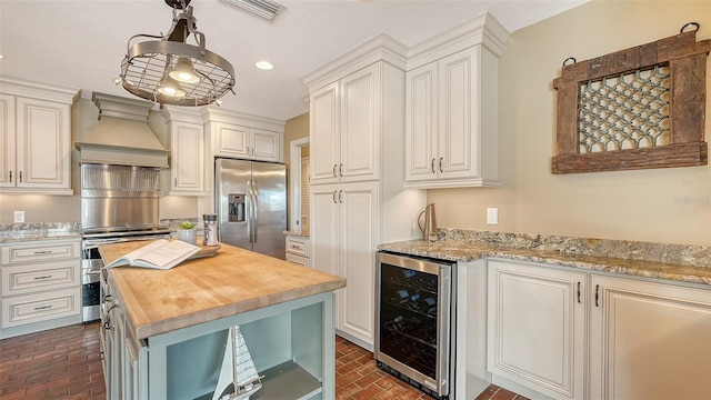 kitchen with wooden counters, stainless steel fridge, beverage cooler, a center island, and hanging light fixtures