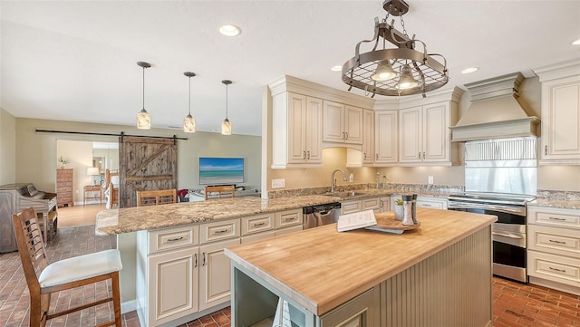 kitchen featuring a center island, sink, stainless steel appliances, a barn door, and premium range hood