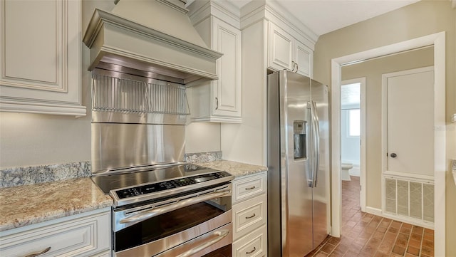 kitchen with appliances with stainless steel finishes, premium range hood, and light stone counters