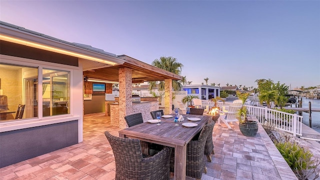 patio terrace at dusk with a fire pit and a water view