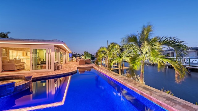 pool at dusk with a patio area and an in ground hot tub