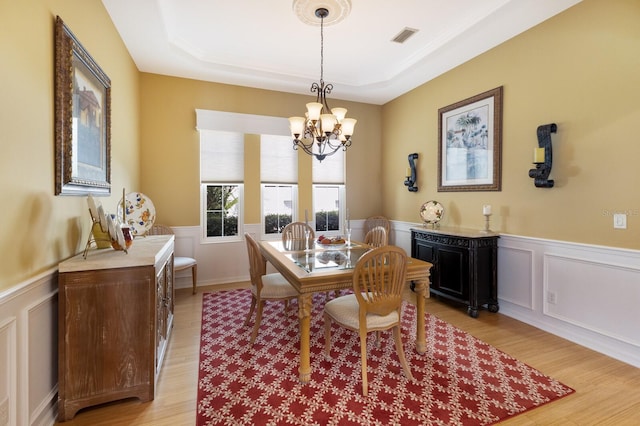 dining area featuring a chandelier, a tray ceiling, and light wood-type flooring