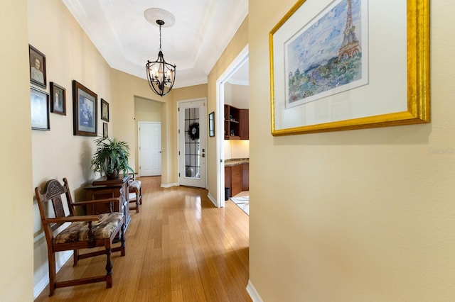 hallway featuring a chandelier, crown molding, and wood-type flooring