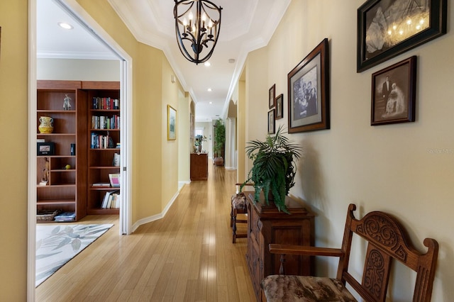 corridor featuring an inviting chandelier, ornamental molding, and light wood-type flooring