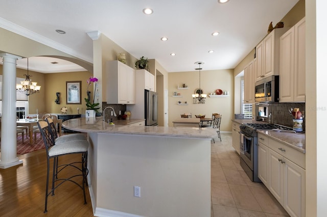 kitchen featuring kitchen peninsula, light hardwood / wood-style floors, pendant lighting, a breakfast bar area, and high end appliances